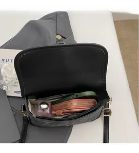 Vue de dessus de l'intérieur spacieux du sac bandoulière noir avec téléphone et portefeuille