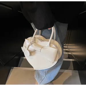 Chic heart-shaped white handbag with large bow accent shown in a street style setting