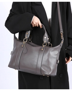 Macro shot of dark grey litchi texture leather handbag with gold rivets and dual handles