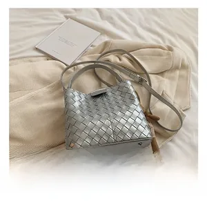 Detail of silver woven bucket bag showing the metal protective studs on the leather base