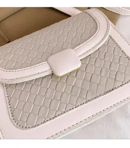 Close-up of the woven texture and square buckle on this stylish pink crossbody flap bag