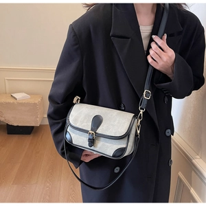 Détail d'un sac bandoulière en toile et cuir avec bandoulière réglable et boucle dorée