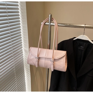 Detail of light pink faux leather baguette bag with dual buckles on a metal hanger