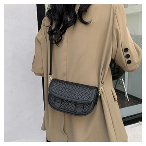 Detail of black woven texture saddle bag with gold metal buckle on model