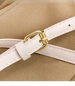 Detail of slim cream leather belt featuring a polished gold metallic pin buckle closure