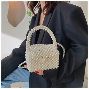 Detail of white handmade pearl beaded crossbody bag styled with a sleek black blazer