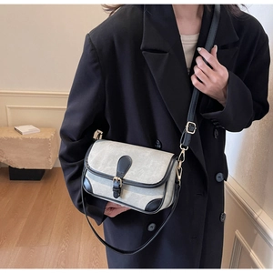 Détail du sac à bandoulière bicolore avec boucle métallique sur tissu gris et cuir noir