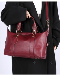 Detail of burgundy lychee leather handbag with gold hardware and detachable strap