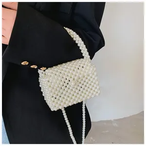 Detail of white handmade pearl beaded handbag showing texture and chain strap