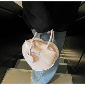 Detail of a pink heart-shaped handbag with a large bow and glossy patent leather finish