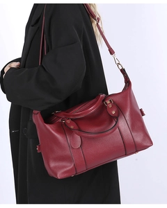 Détail du sac à main en cuir bordeaux à grain litchi sur un manteau noir élégant