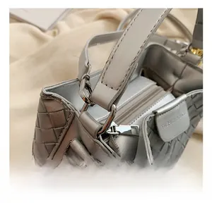 Detail view of silver metal hooks and smooth zipper on a grey woven bucket bag