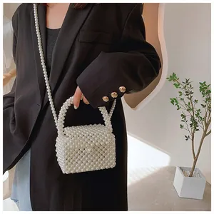 Detail view of handmade white pearl beaded square handbag on a black blazer background