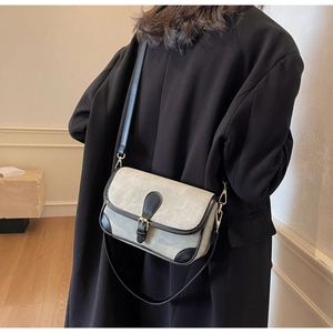 Vue latérale du sac bandoulière gris-vert avec bordure noire et boucles dorées sur modèle