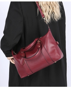 Detail of burgundy lychee leather pillow bag with gold hardware and adjustable strap