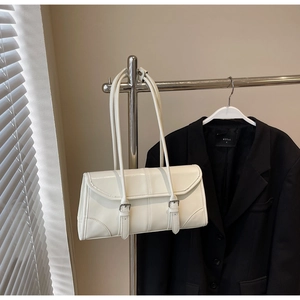 Detailed view of a white leather underarm bag featuring dual straps on a sleek metal stand