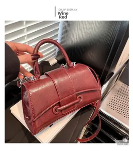 Detail of burgundy hourglass handbag in oil wax leather with top handle and strap