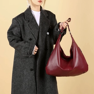 Grand sac hobo en cuir bordeaux pour femme porté avec un manteau d'hiver gris chiné