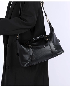 Detail of black pebbled leather tote with gold hardware shown on a shoulder strap
