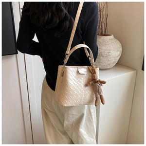 Detail of cream woven bucket bag with magnetic closure and plaid bunny pendant charm