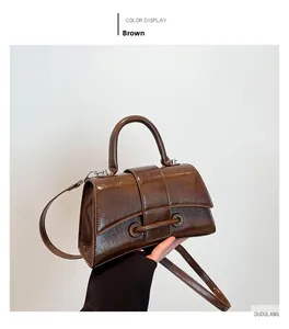 Detail of dark brown glossy wrinkled texture and trapezoidal silhouette hourglass bag