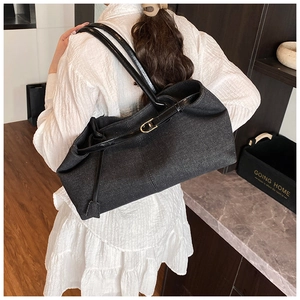 Detalle de un bolso tote negro grande con correa de cuero y hebilla metálica