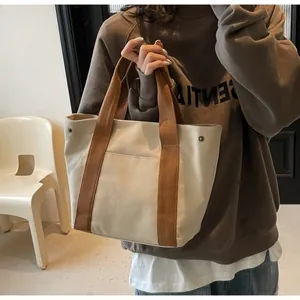 Detailed shot of beige canvas tote bag with brown woven handles and rivet reinforcement