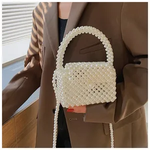 Detail of white handmade pearl beaded crossbody bag with elegant flap and pearl strap