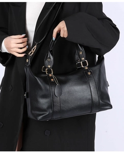 Close-up of black litchi pattern leather tote bag with gold hardware and shoulder strap