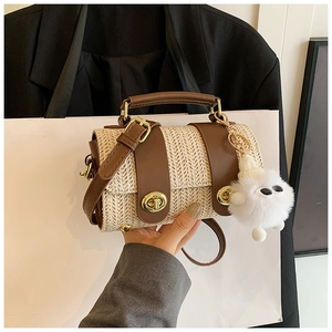 Detail of woven cylindrical handbag with brown leather trim and plush charm
