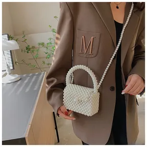 Detailed side view of white handmade pearl beaded crossbody bag styled with a brown blazer