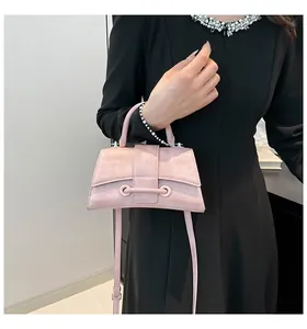 Close-up of pink textured hourglass handbag with metal buckle and shoulder strap detail