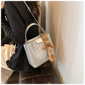 Detail showing silver woven texture bucket bag with a cute plush rabbit charm