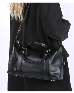 Détail du sac Boston en cuir grainé noir avec finitions dorées et clous élégants