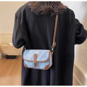 Détail du sac à bandoulière en denim et cuir marron avec une sangle réglable