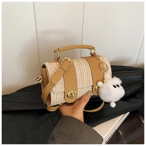 Close-up of beige woven handbag with brown leather trim and cute monster plush charm