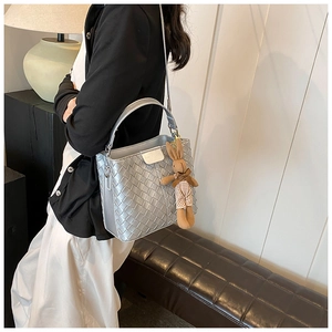 Detail shot of silver woven bucket bag featuring metal texture and cute bunny pendant