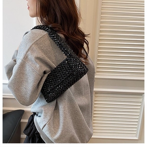 Detailed view of handmade black beaded shoulder bag worn over a grey sweatshirt