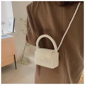 Detailed view of a handmade pearl woven crossbody bag on a brown blazer outfit