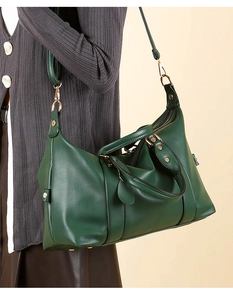Detail of dark green pebble leather tote bag featuring gold hardware and adjustable strap
