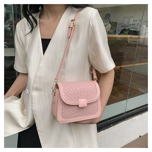 Detailed view of a pink woven texture crossbody bag on a female model in white clothing