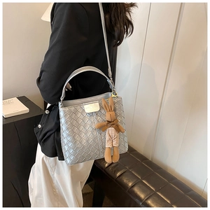 Detail of silver woven bucket bag with magnetic closure and cute rabbit charm accent