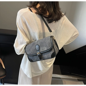 Détail d'un sac bandoulière bicolore avec boucle métallique et texture en similicuir