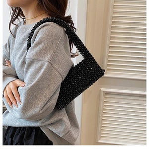 Detail of hand-woven black beaded shoulder bag worn with casual minimalist outfit
