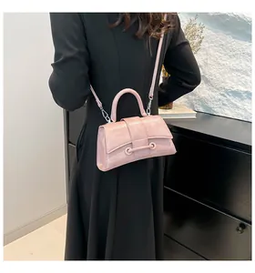 Pink glossy leather hourglass handbag worn by a model in a black dress with a crossbody strap