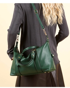 Détail du sac à main en cuir grainé vert foncé avec ferrures dorées et bandoulière réglable