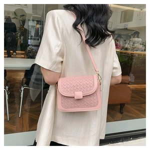 Detail of light pink woven crossbody bag with gold hardware shown on a female model