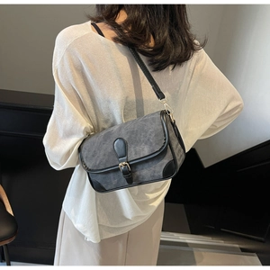 Détail du sac bandoulière gris avec bordure noire et boucle dorée porté par mannequin