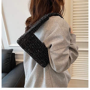Detail of hand-woven black beaded shoulder bag featuring a glossy texture and retro style