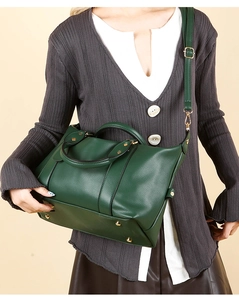 Detail of dark green pebble leather pillow bag with gold hardware and bottom metal studs